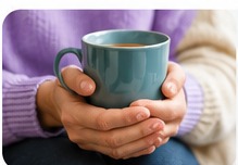 Hands holding a warm drink during a supportive conversation
